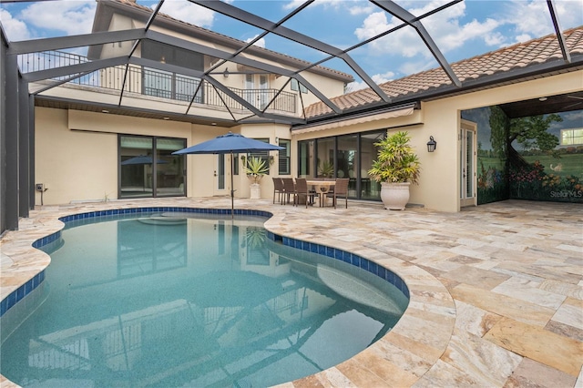 pool featuring outdoor dining space, glass enclosure, and a patio