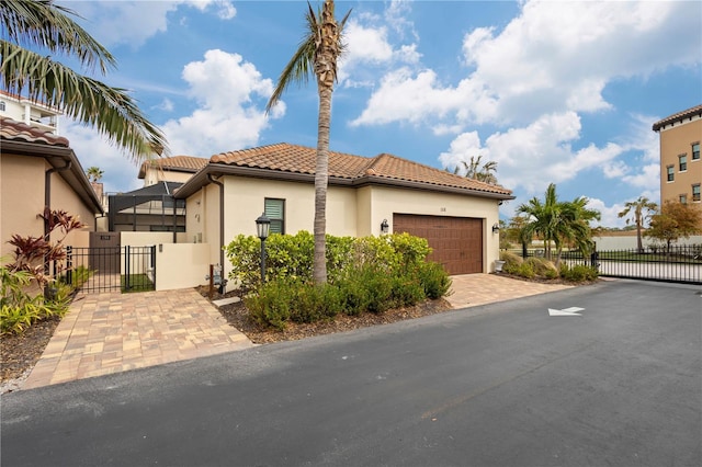 view of front of home featuring a tile roof, stucco siding, a gate, fence, and a garage