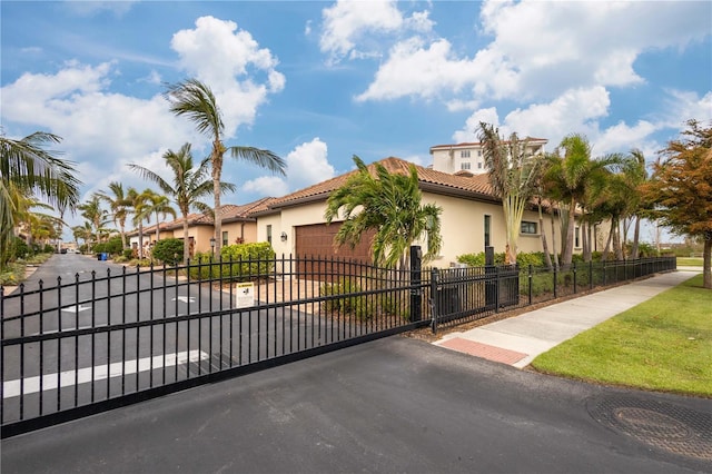 mediterranean / spanish home with a fenced front yard, stucco siding, a gate, a garage, and driveway