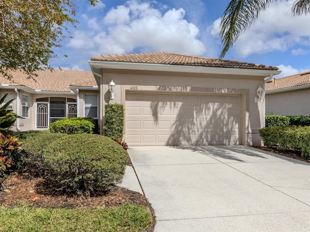 view of front facade with concrete driveway, a tiled roof, an attached garage, and stucco siding