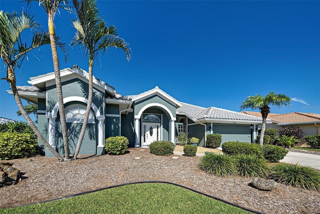 ranch-style home with a garage, concrete driveway, a tile roof, and stucco siding