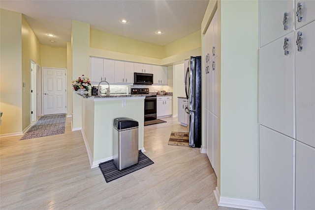 kitchen featuring light wood-style flooring, a peninsula, white cabinets, appliances with stainless steel finishes, and tasteful backsplash