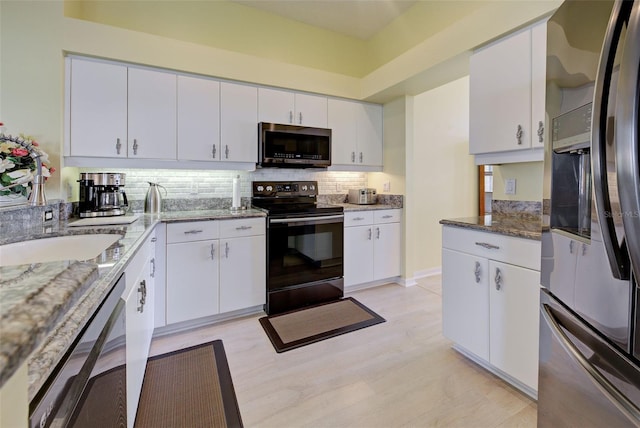 kitchen with light wood-style flooring, white cabinets, appliances with stainless steel finishes, tasteful backsplash, and dark stone countertops