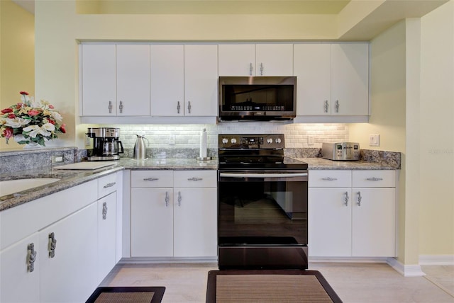 kitchen with white cabinets, electric range oven, stainless steel microwave, light stone countertops, and backsplash