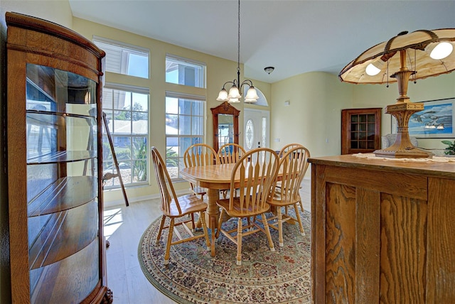 dining space with light wood-type flooring, an inviting chandelier, and baseboards