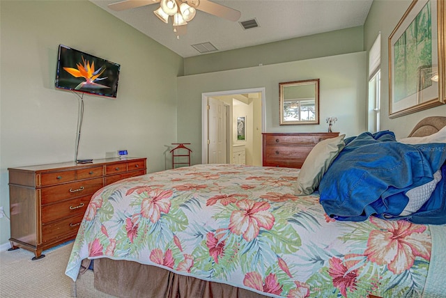 bedroom with lofted ceiling, light colored carpet, visible vents, a ceiling fan, and ensuite bath