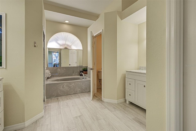 full bathroom with wood finished floors, vanity, baseboards, and a bath