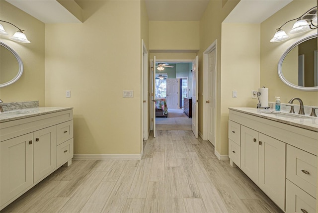 ensuite bathroom featuring baseboards, a sink, and wood finished floors