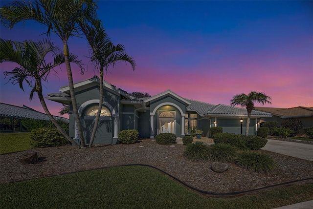 view of front of home with a garage, driveway, a tiled roof, and stucco siding