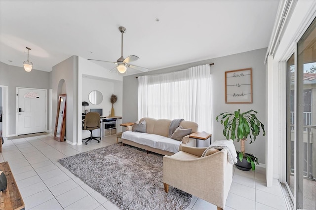 living room featuring light tile patterned floors, plenty of natural light, arched walkways, and a ceiling fan