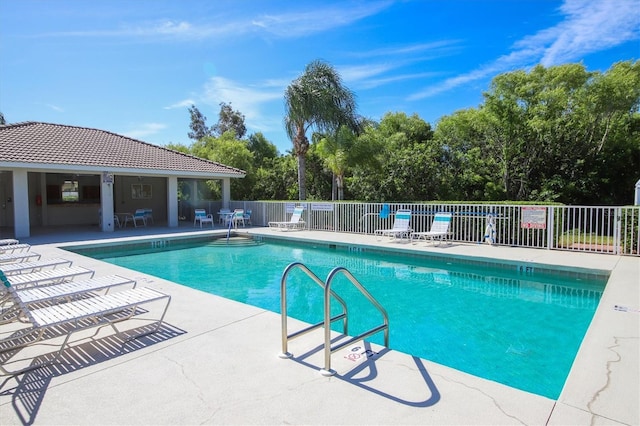 community pool with a patio area and fence