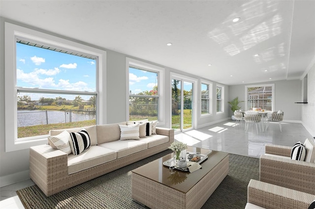 living area with recessed lighting, baseboards, a healthy amount of sunlight, and a water view