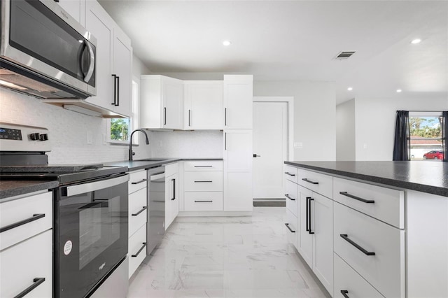 kitchen with dark countertops, marble finish floor, stainless steel appliances, and a sink