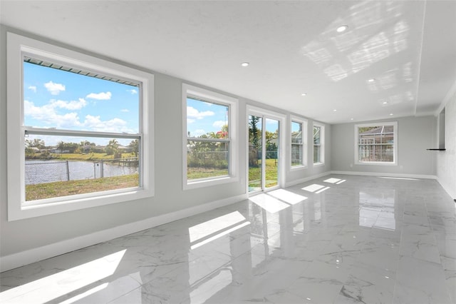 unfurnished living room with recessed lighting, baseboards, a water view, and marble finish floor