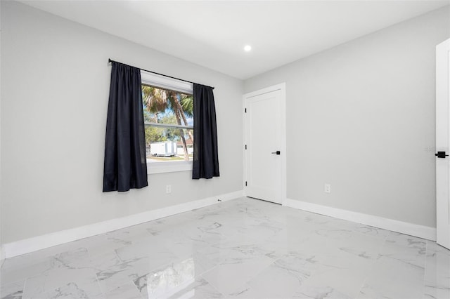 spare room featuring recessed lighting, baseboards, and marble finish floor