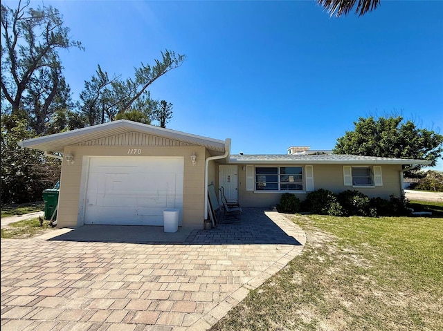 single story home featuring a garage, a front yard, and decorative driveway