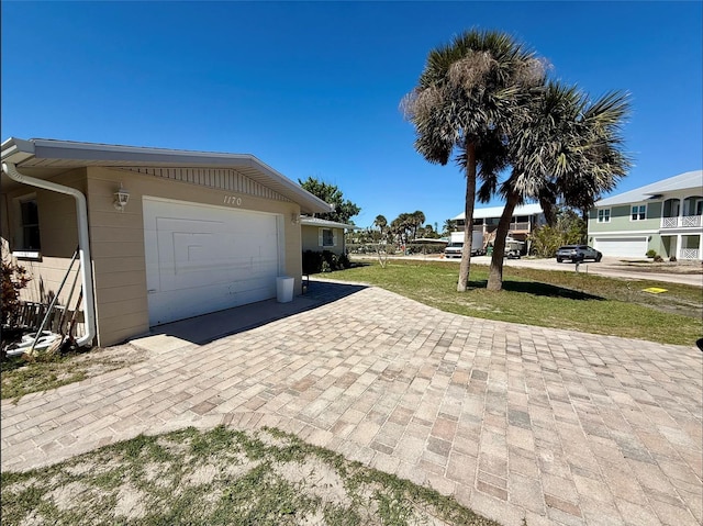 view of side of home with a garage, a yard, and decorative driveway