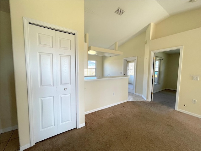 tiled spare room featuring visible vents, baseboards, carpet, and lofted ceiling