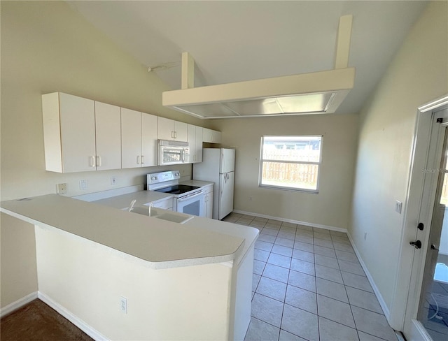 kitchen with light countertops, a peninsula, light tile patterned flooring, white appliances, and a sink