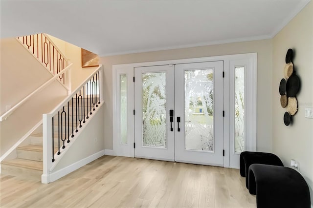 foyer entrance featuring wood finished floors, french doors, crown molding, baseboards, and stairs