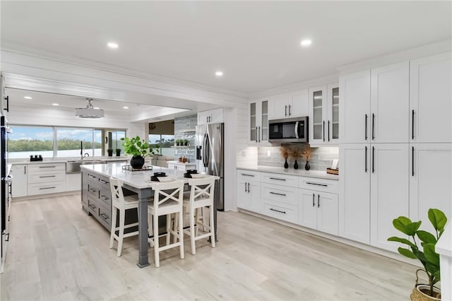 kitchen with stainless steel appliances, light countertops, white cabinets, glass insert cabinets, and tasteful backsplash