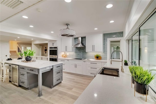 kitchen with beverage cooler, white cabinets, wall chimney exhaust hood, and black electric cooktop