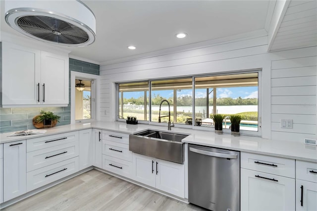 kitchen with light wood-style flooring, a sink, light countertops, dishwasher, and crown molding