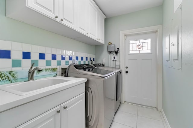 laundry room with washing machine and clothes dryer, electric panel, light tile patterned flooring, cabinet space, and a sink