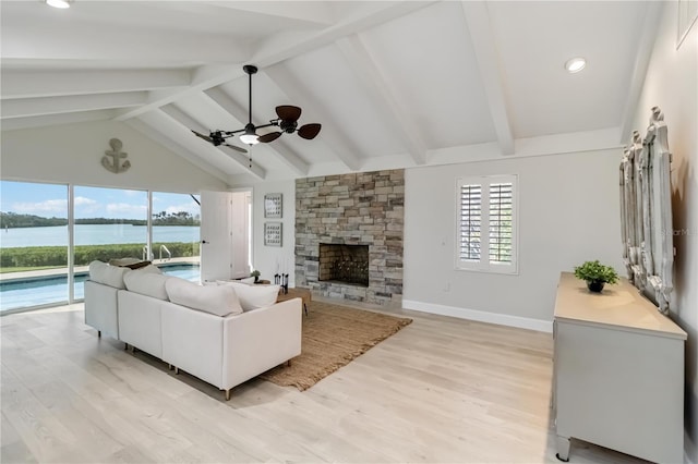 living area with a stone fireplace, vaulted ceiling with beams, light wood-style floors, and a water view