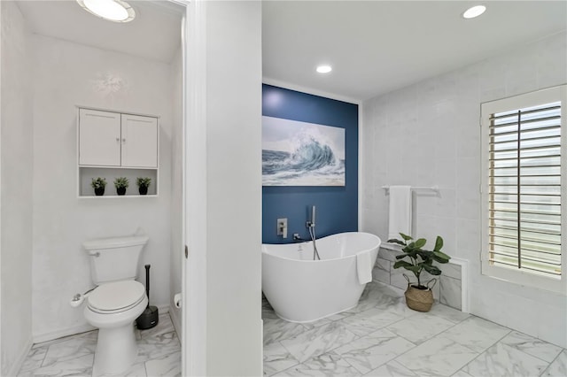 bathroom featuring baseboards, recessed lighting, a freestanding bath, toilet, and marble finish floor