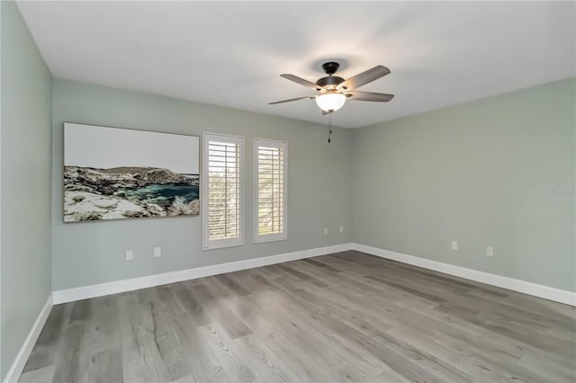 empty room featuring baseboards, wood finished floors, and ceiling fan