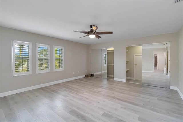 unfurnished bedroom featuring light wood-type flooring, baseboards, multiple closets, and a ceiling fan