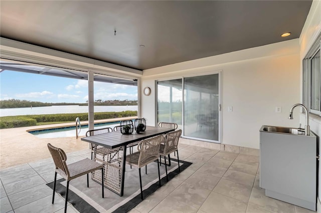 sunroom / solarium with a water view and a sink