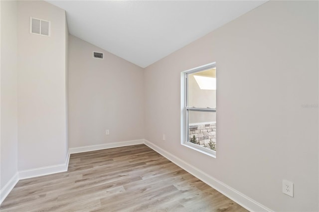 spare room with lofted ceiling, baseboards, visible vents, and light wood-type flooring