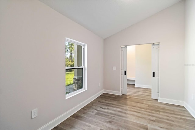 spare room with baseboards, wood finished floors, and vaulted ceiling