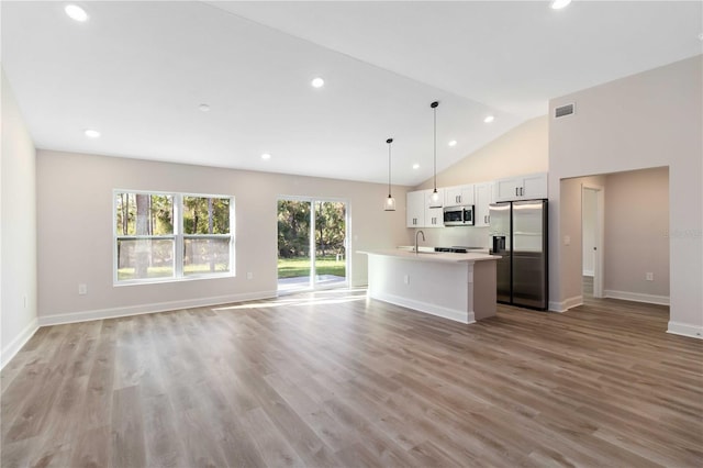 kitchen with a sink, appliances with stainless steel finishes, open floor plan, and a center island with sink