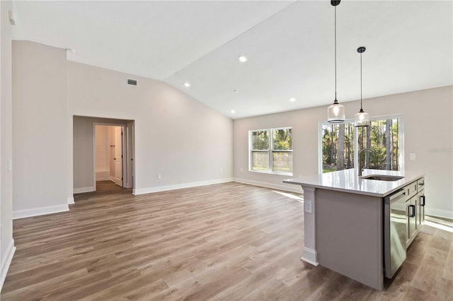 kitchen with a sink, light wood-style floors, light countertops, lofted ceiling, and hanging light fixtures