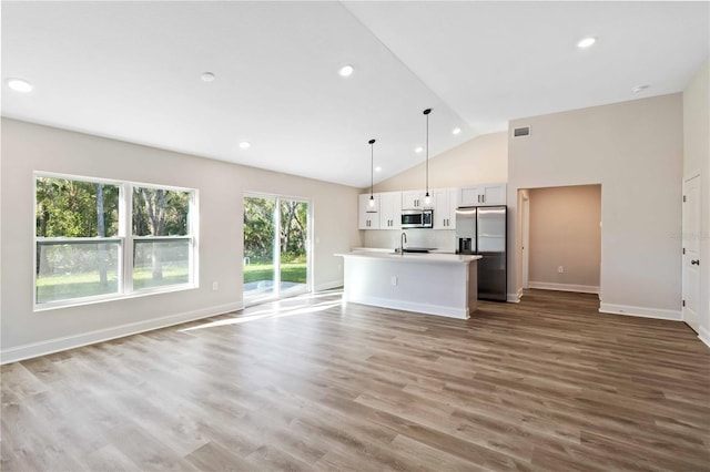 unfurnished living room with recessed lighting, wood finished floors, baseboards, and a sink