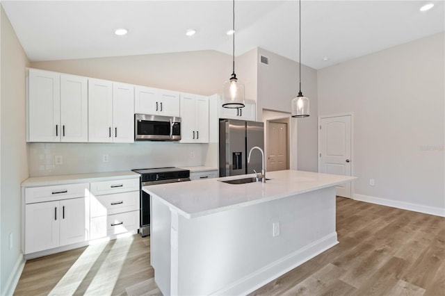 kitchen featuring an island with sink, a sink, appliances with stainless steel finishes, white cabinetry, and light wood-type flooring