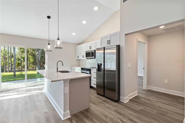 kitchen featuring visible vents, a center island with sink, a sink, wood finished floors, and appliances with stainless steel finishes