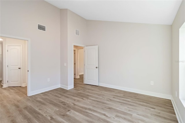 unfurnished bedroom featuring light wood finished floors, visible vents, high vaulted ceiling, and baseboards