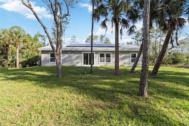 view of front facade featuring solar panels, a front yard, and stucco siding