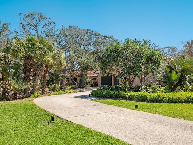 view of community with an attached garage, concrete driveway, and a yard