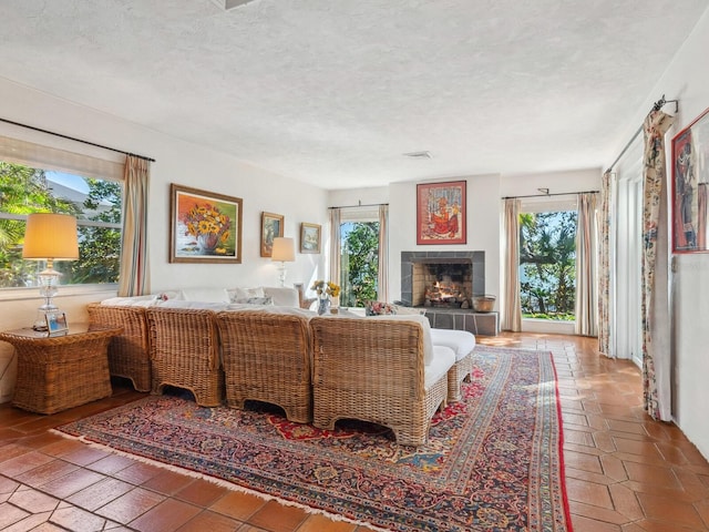 living room featuring a tiled fireplace, a wealth of natural light, and a textured ceiling