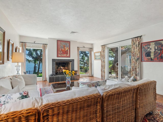 living area with a fireplace, visible vents, and a textured ceiling