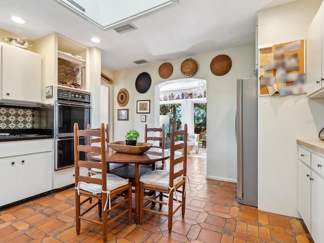 dining area featuring arched walkways, visible vents, and recessed lighting