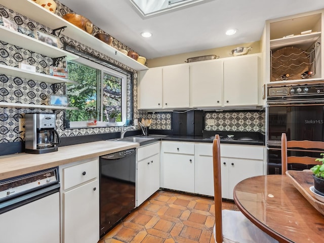 kitchen with backsplash, white cabinetry, black appliances, and a sink