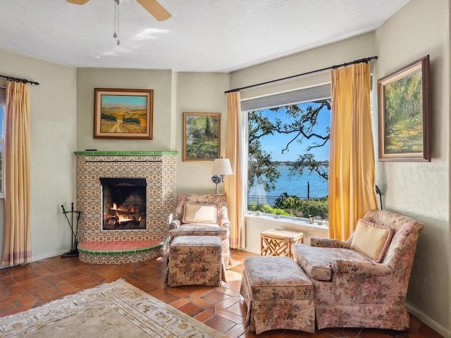 living area with a healthy amount of sunlight, a fireplace, a ceiling fan, and baseboards