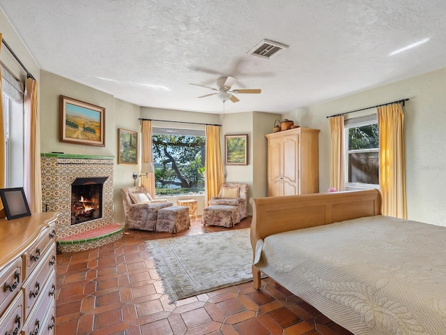 bedroom with visible vents, multiple windows, a textured ceiling, and a fireplace