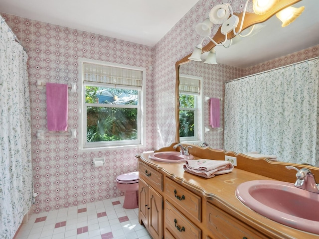 bathroom with toilet, wallpapered walls, a shower with curtain, and a sink